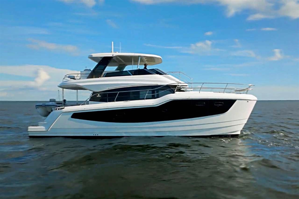 A sleek white and black yacht navigates calm waters under a clear blue sky, showcasing luxury boat design and aesthetics.